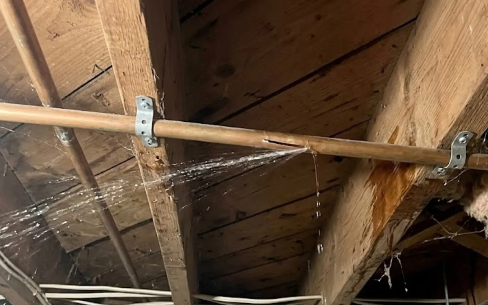 burst copper pipe spraying water inside a wall