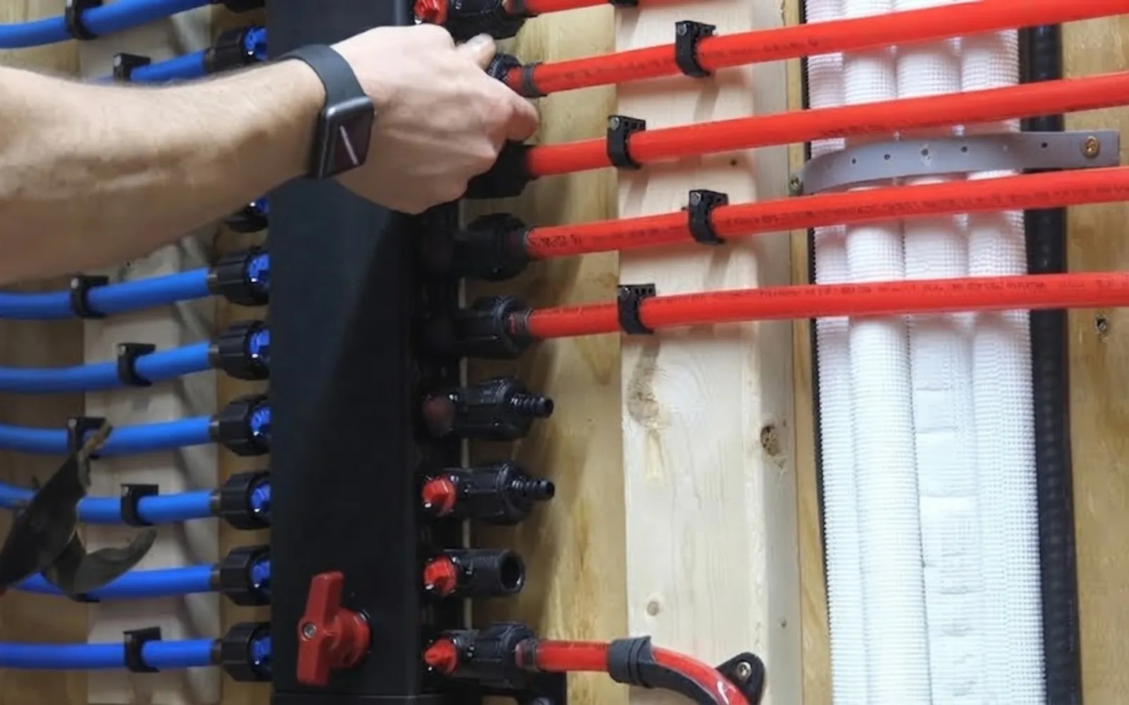new red and blue PEX pipes installed in an open wall during a repipe