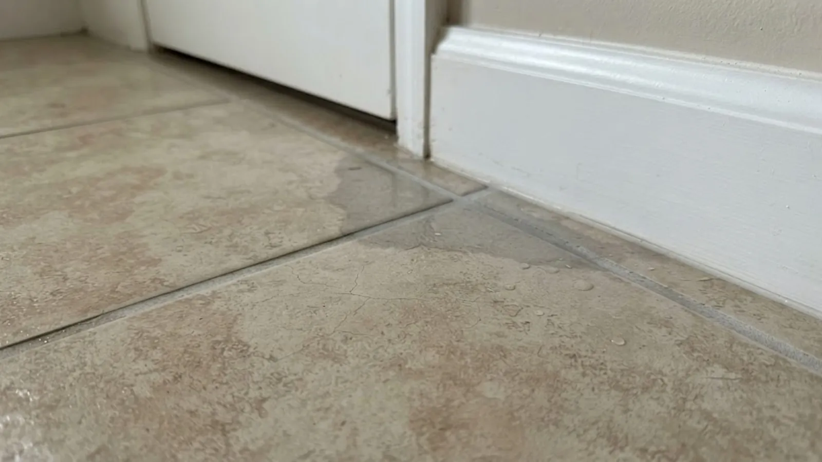 damp tile floor near a baseboard from a slab leak